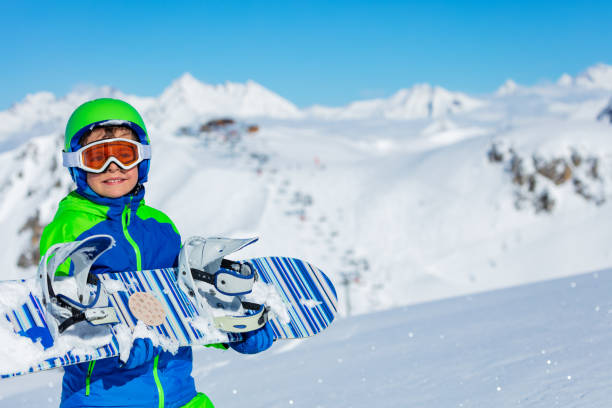 istock Cute little boy hold snowboard over mountain 1249976170
