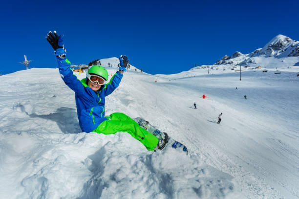 istock Little boy with snowboard lift hands sit by slope 1249976200