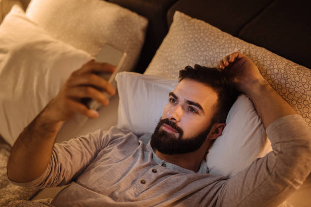 istock Handsome bearded man using phone in the bed at night 1249979060