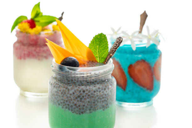 Healthy breakfast colorful yogurt glass containers with strawberries berries and flowers on white