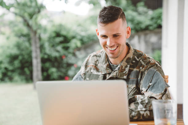 ミッションから家に電話する軍の制服を着た笑顔の男 - military man ストックフォトと画像