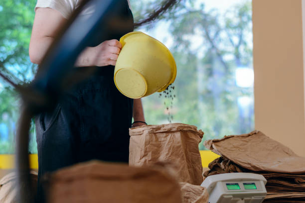 istock Worker in apron pouring coffee beans into bag 1249991364