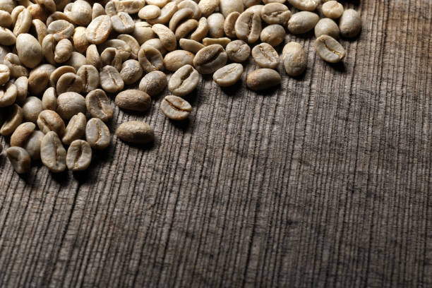 Unroasted  green coffee beans on wooden background - Close up stock photo