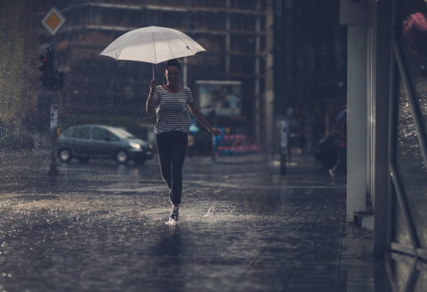 młoda beztroska kobieta biegająca po ulicy w deszczowy dzień. - puddle street water women zdjęcia i obrazy z banku zdjęć