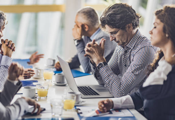 istock Tired businessman reading an e-mail on a meeting with his colleagues. 1249992843