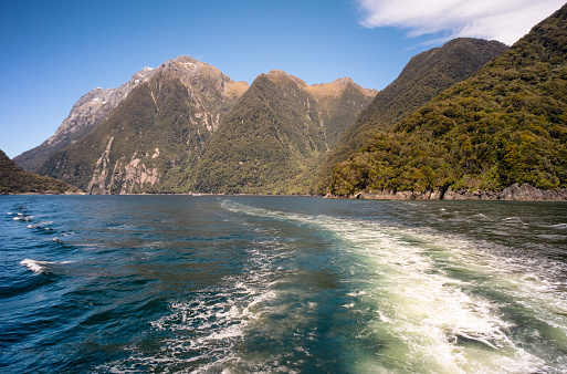 A sunny day in Milford Sound, New Zealand, and this is the view from a tourist cruise ship as it cruises through the magnificent fjords of the Fiordland National Park.