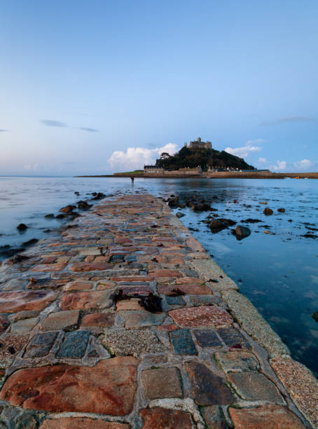 Photographing St Michael's Mount In Cornwall Early morning light reveals the causeway that leads to the Cornish landmark that is St Michael's Mount. At the end of the causeway, a photographer prepares to take his shot. marazion photos stock pictures, royalty-free photos & images