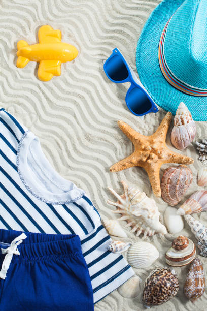 istock Sea background. Sea shells flat lay with white sand and child`s clothes on it 1249998140