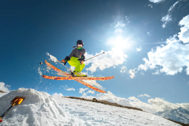Girl skier in flight after jumping from a kicker in the spring against sun and blue sky. Close-up wide angle. stock photo