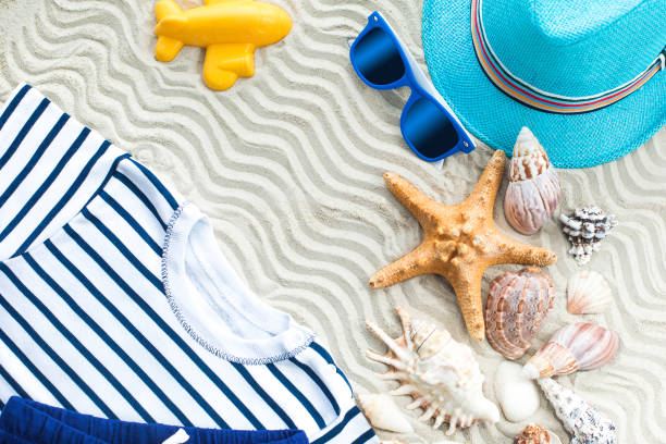 istock Sea background. Sea shells flat lay with white sand and child`s clothes on it 1249998902