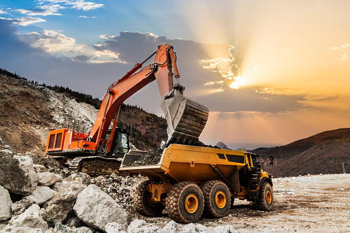 Earth mover plunges raw materials into a dump truck stock