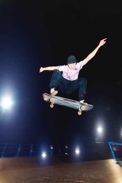 un giovane pattinatore di notte in uno skatepark fa il trucco sulla ringhiera. concetto di vita notturna della cultura a raggi x - rolling up flash foto e immagini stock