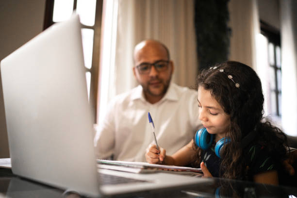 Father helping daughter doing her homework on video chat e-learning at home