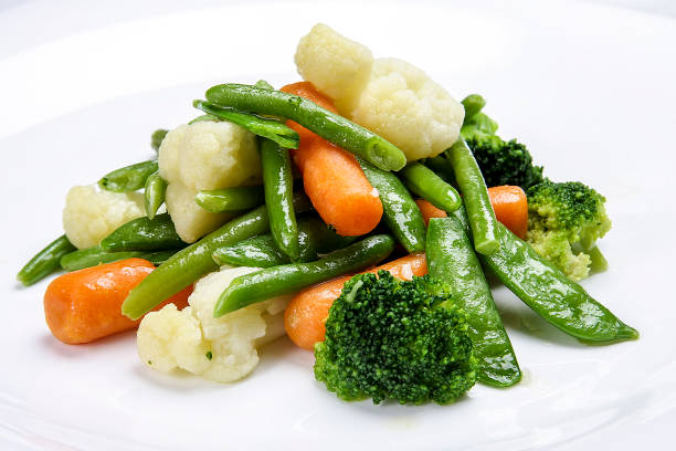 verduras al vapor sobre fondo blanco. coliflor, guisantes, brócoli, zanahorias y frijoles espárragos. - hervido fotografías e imágenes de stock