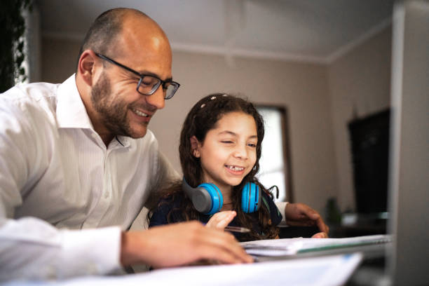 istock Father helping daughter doing her homework on video chat e-learning at home 1250004534