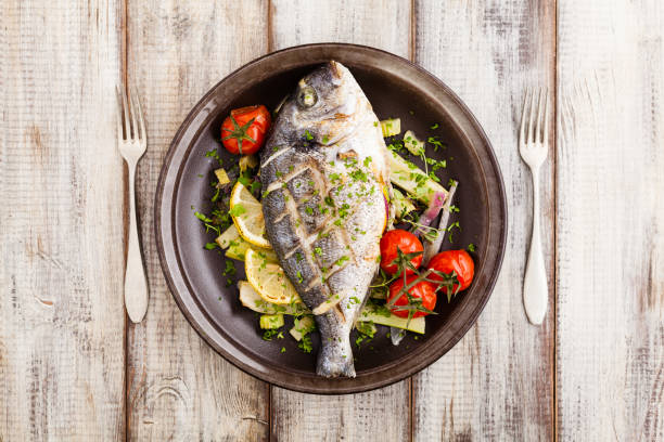 istock Baked whole fish, served with roasted vegetables and lemon. 1250008042
