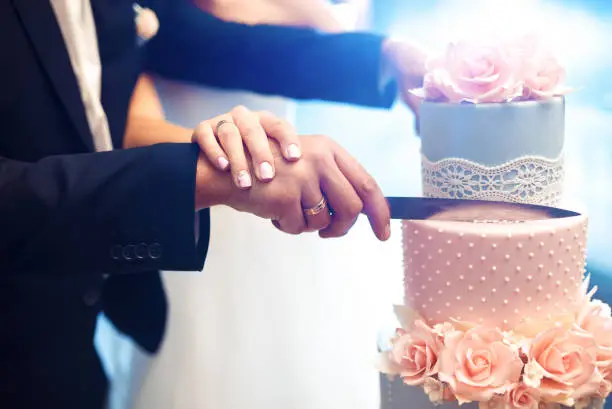 Photo of A bride and a groom is cutting their wedding cake.