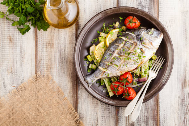 istock Baked whole fish, served with roasted vegetables and lemon. 1250008341