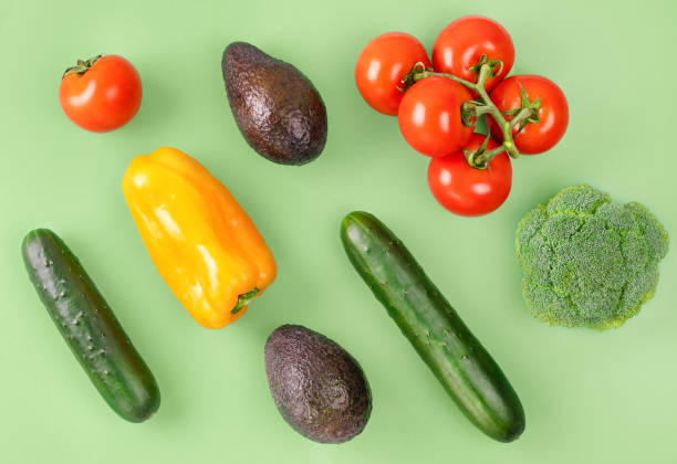 istock Vegetable creative layout on green background. Tomatoes branch, orange bell pepper, avocado, cucumber, broccoli. Vegetarian healthy food concept. 1250018752