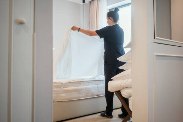 cameriera che fa il letto, prepara la camera d'albergo per gli ospiti - home interior sparse bedroom inside of foto e immagini stock