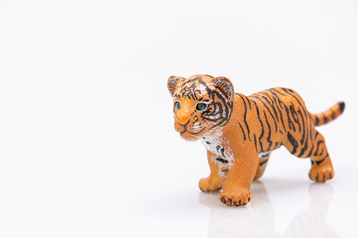 close up of a plastic baby tiger toy isolated on a white background