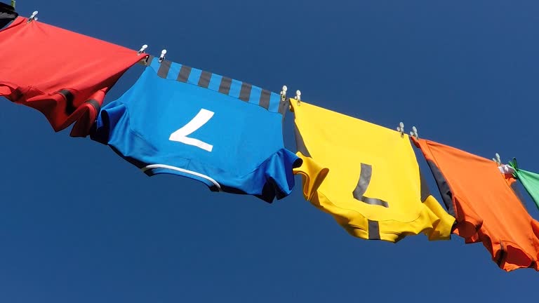 Clean colourful sports shirts drying on a washing line.