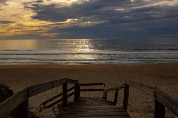 View of empty beach and part of wooden handrail at sunset a few minutes before dark. Quiaios beach, Portugal.