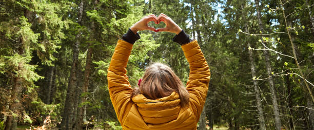 mujer con símbolo en forma de corazón que se sostiene en el aire en el entorno natural. - heart shape loneliness women praying fotografías e imágenes de stock