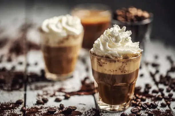 Photo of Black coffee with whipped cream in glass cups and spilled coffee beans