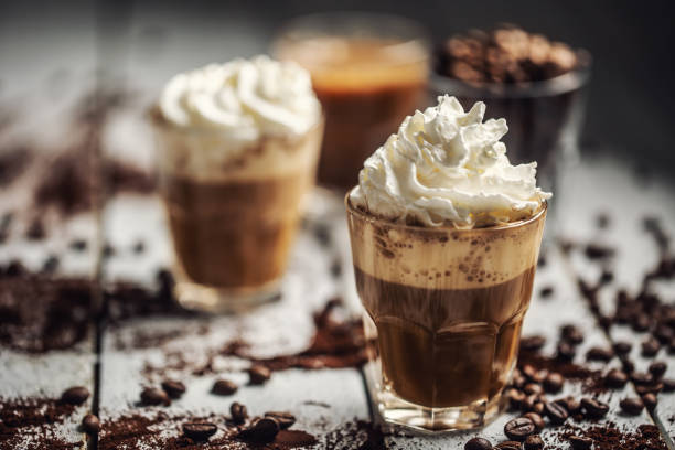 black coffee with whipped cream in glass cups and spilled coffee beans - caramel latté coffee cafe macchiato imagens e fotografias de stock