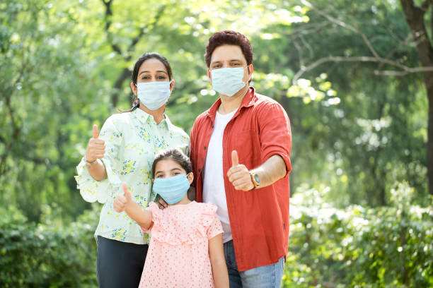 Family with protective face mask giving thumbs up at park Family with protective face mask giving thumbs up at park pathogen photos stock pictures, royalty-free photos & images