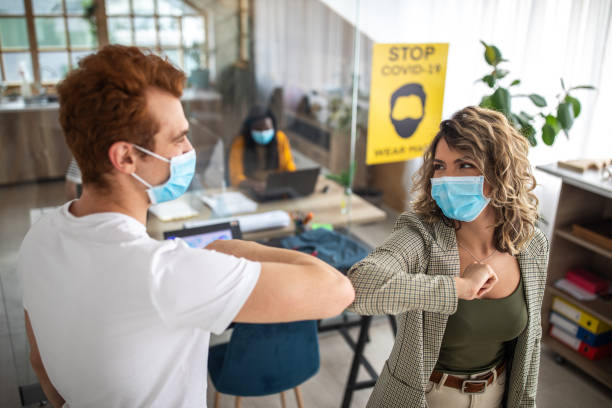 istock Colleagues greeting each other with elbow bump at office 1250025714