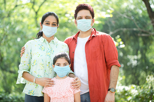 Family with protective face mask at park