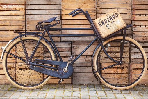 Vintage black cargo transport bicycle with crate carrier in front of old wooden crates