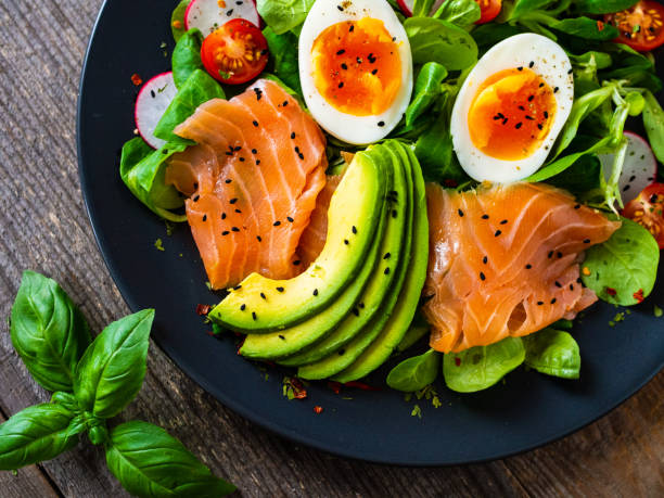 istock Smoked salmon with boiled eggs, avocado and vegetables on wooden table 1250027053