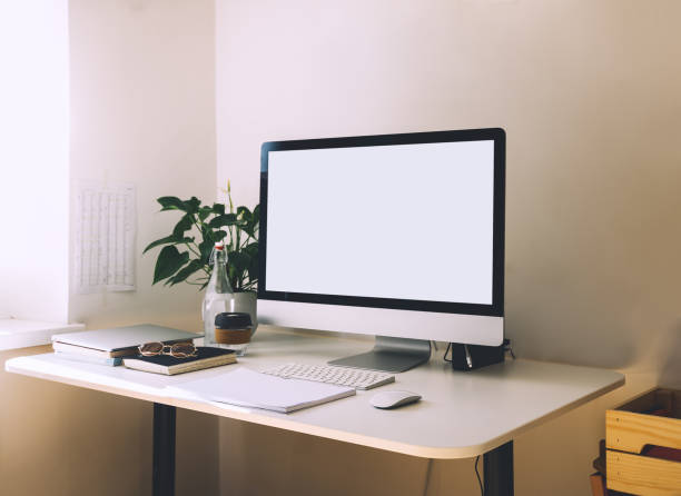 istock Work place concept. Stylish workspace with computer at home. Mock up blank white screen computer desktop with keyboard, mug, book, plant, framed photos on wall in office room. 1250027060