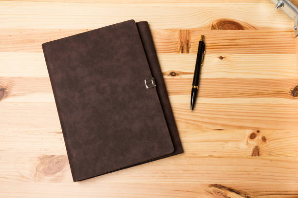 istock Leather-bound business notebook with a pen on wooden background. 1250031041