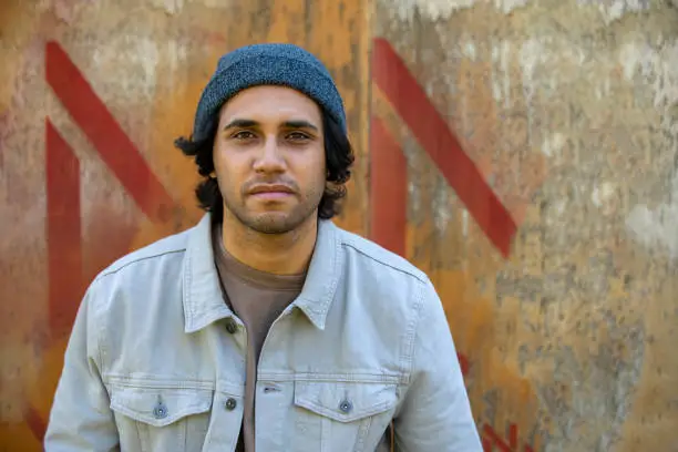 Portrait of a happy young aboriginal man on an industrial background.