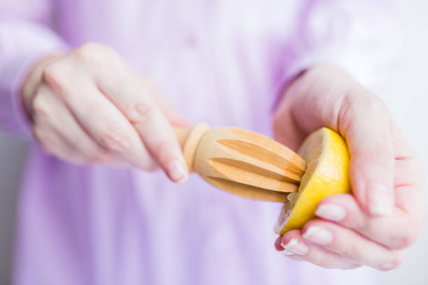 Close up of woman squeezing lemon with wooden squeezer. Healthy eating and fruits concept.