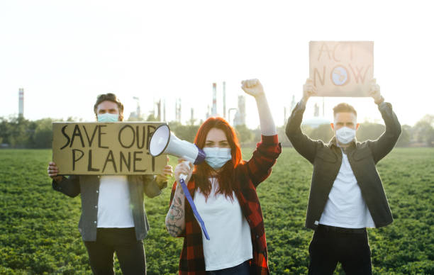 istock Group of young activists with placards standing outdoors by oil refinery, protesting. 1250033850