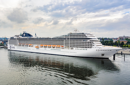 Cruise ship MSC Poesia operated by MSC Cruises moored in the port of Kiel in Germany on a summer day. The MSC Poesia of the Musica-class design, was constructed by STX Europe at a cost of $547 million and is 293.8 metres long and has 1,259 cabins with a capacity of  3,605 passengers and 1,027 crew members