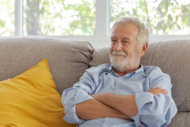 istock Happy senior retirement old man smiling while sitting at the sofa in his home 1250035182