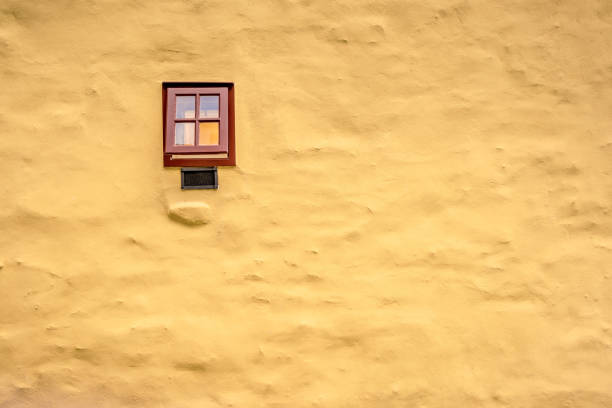 istock Small brown window on the yellow masonry wall 1250035254