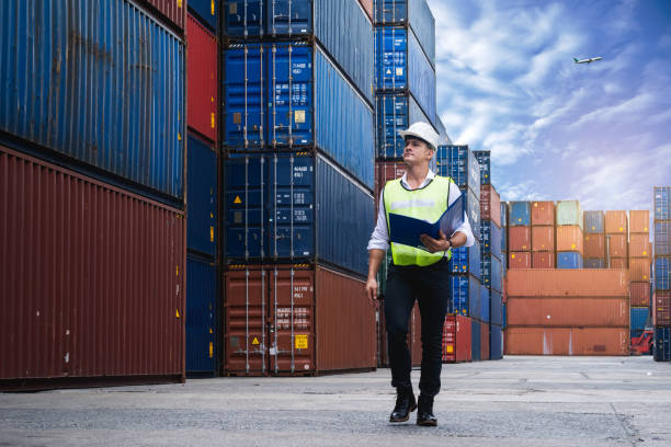 responsabile in possesso di un documento, a piedi e a controllo della scatola dei container dalla nave da carico per l'esportazione e l'importazione - harbor commercial dock shipping container foto e immagini stock