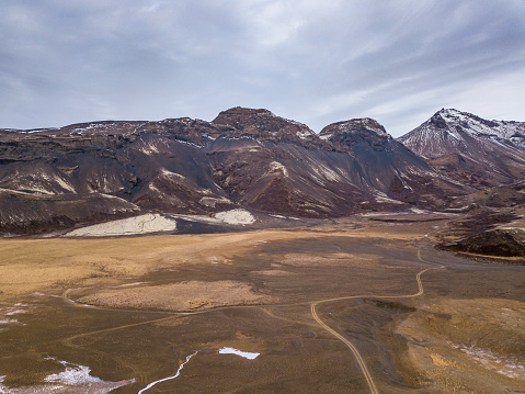 drone point of view of iceland dirt road and mountain range.