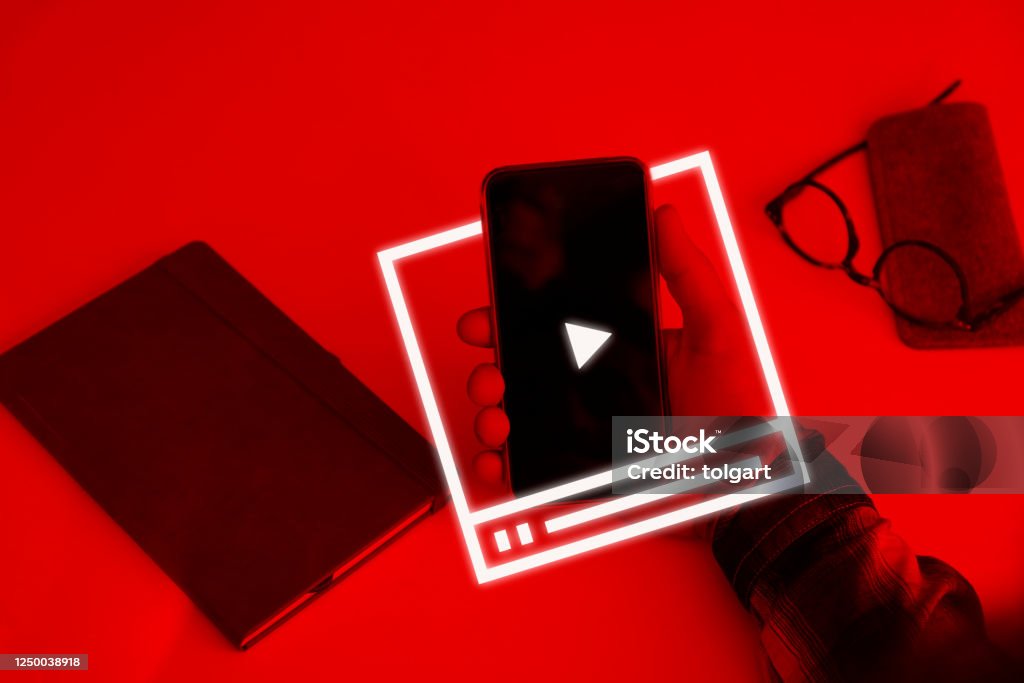 Video Marketing Concept.Hand pressing transparent white button Hand holding smartphone with video player on the screen Home Video Camera Stock Photo