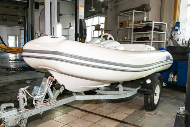 Preparing for the summer season in the garage in the winter on the lift of a motor boat - a white boat for maintenance in the workshop for preparing for yachting - cleaning and polishing the bottom. Preparing for the summer season in the garage in the winter on the lift of a motor boat - a white boat for maintenance in the workshop for preparing for yachting - cleaning and polishing the bottom. motorboat maintenance stock pictures, royalty-free photos & images