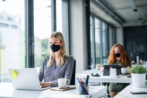 istock Young people with face masks back at work or school in office after lockdown. 1250042710
