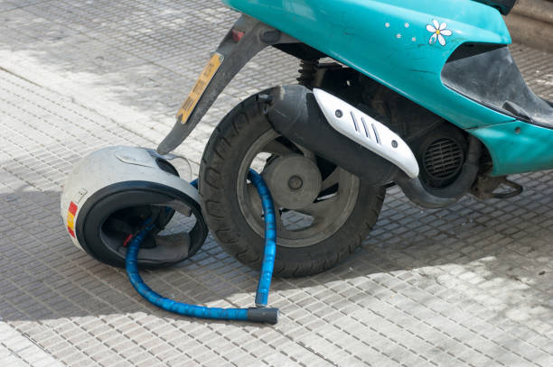 Used scooter chained to a helmet lying on the sidewalk