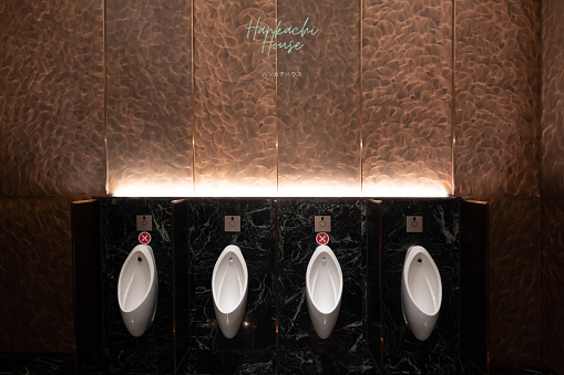 Urinal area with sign of social distancing with copper wall on the background / interior concept / new normal